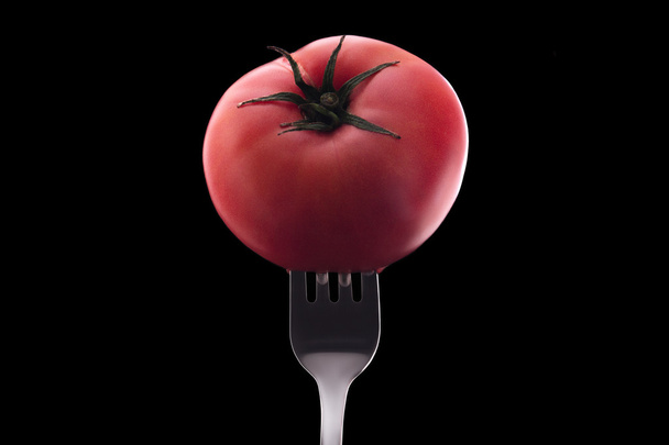 red tomato impaled on a silver fork - Фото, изображение