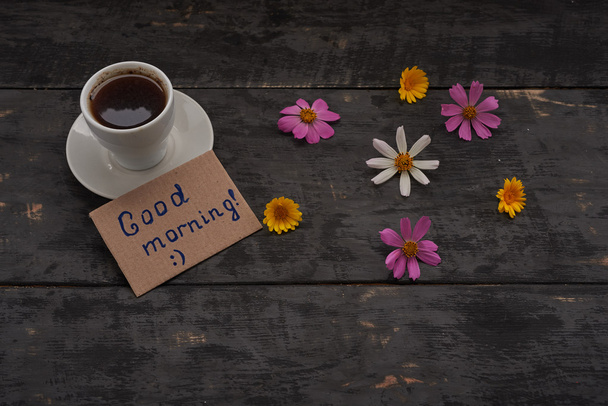 csésze kávé jó reggelt jel és a virágok az asztalon - Fotó, kép