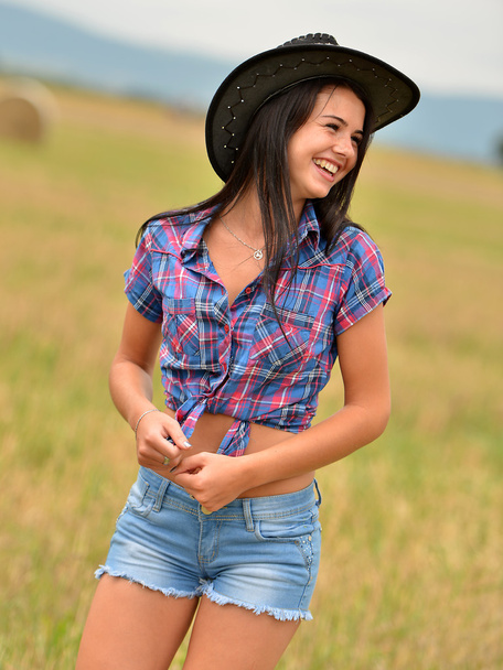 Una giovane cowgirl che sogna ad occhi aperti in un campo di fieno
 - Foto, immagini