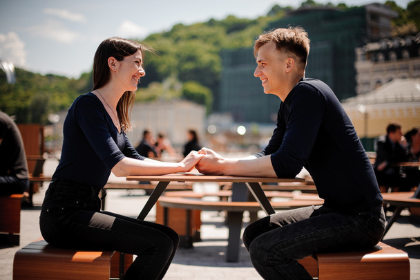 Young, happy couple smiling and holding hands across the table at a restaurant. - Fotografie, Obrázek