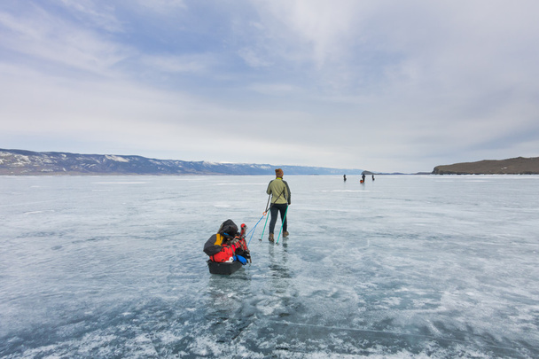 Girl with a sledge and trekking pole is on the ice of Lake Baika - 写真・画像