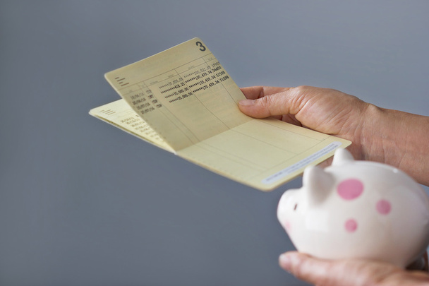 ihmisen hallussa säästötili passbook ja säästöpossu käsissä
 - Valokuva, kuva