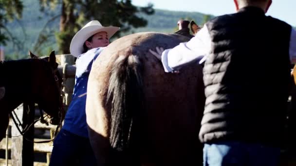 Cowgirl siodłania konia - Materiał filmowy, wideo