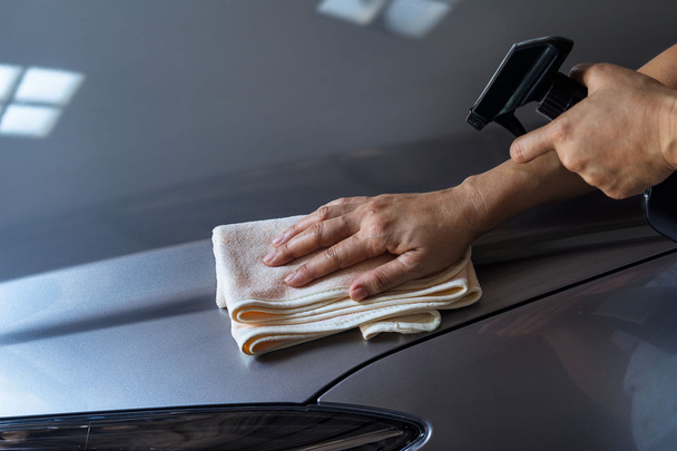 woman cleaning car with microfiber cloth and cleaning spray - Valokuva, kuva