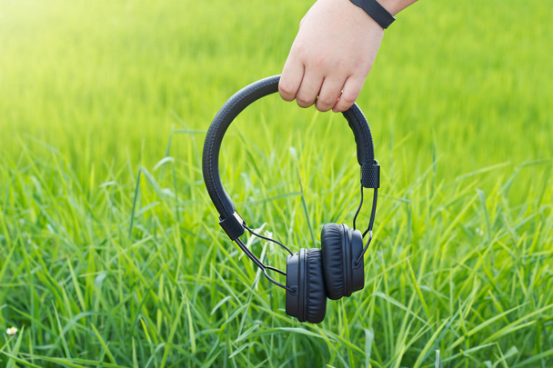 menino mão segurando fone de ouvido sem fio no fundo natureza verde
 - Foto, Imagem