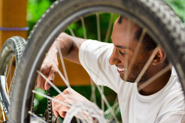 Man wearing white shirt happy working on repairing bicycle mechanics using screwdriver tool - Foto, Bild