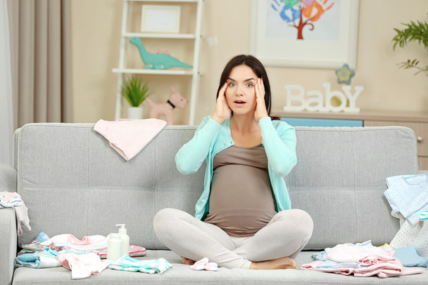 Pregnant woman with baby clothes - Foto, imagen
