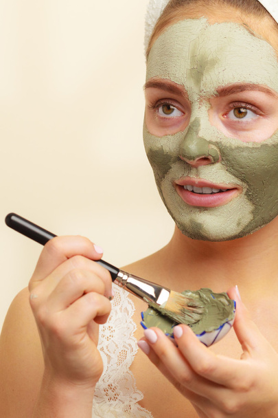 Woman applying with brush clay mud mask to her face  - Foto, afbeelding