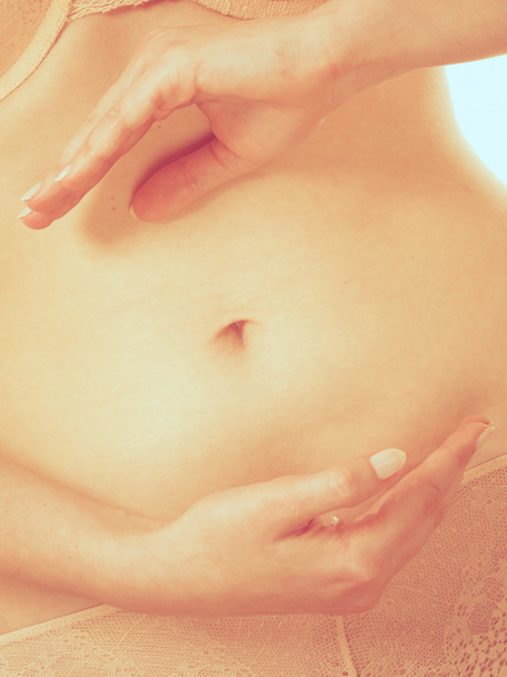 Female hands forming shape on belly. - Foto, immagini