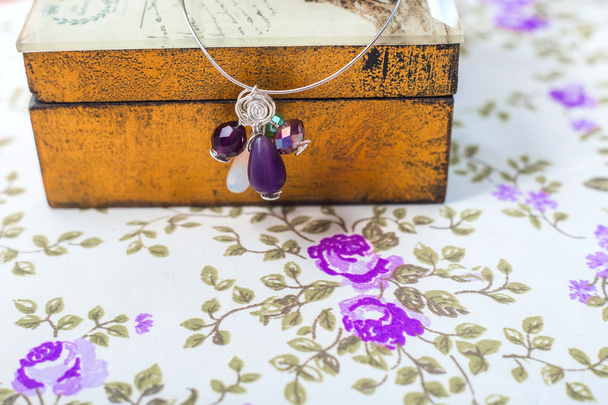 hopeinen riipus luonnonkivet, muotoinen helmiä ja kiteitä violetti tekstiili tausta
 - Valokuva, kuva