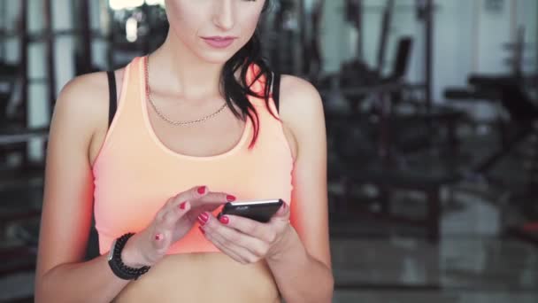 Happy woman using phone in the gym and smiling on a camera - Imágenes, Vídeo
