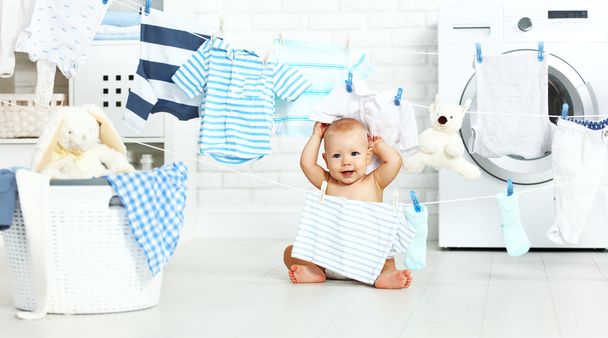 fun happy baby boy  to wash clothes and laughs in laundry - Photo, Image