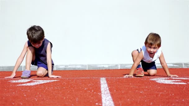 Vídeo divertido con dos niños pequeños preparándose para correr en una pista atlética
 - Imágenes, Vídeo