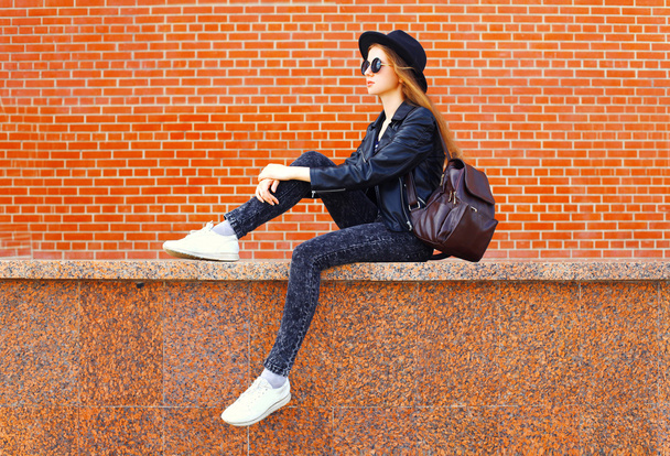 Fashion young woman wearing a black rock style sitting over bric - Φωτογραφία, εικόνα