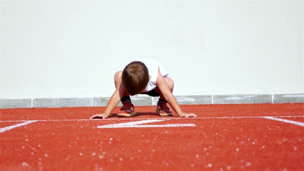 Funny video with a 2 years old boy preparing to run in an athletic track - Footage, Video