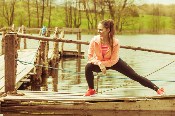 Girl training in sporty clothes on lake shore - Фото, зображення