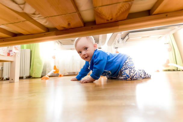 Kisfiú mászik a padlón, és keresi az ágy alatt - Fotó, kép