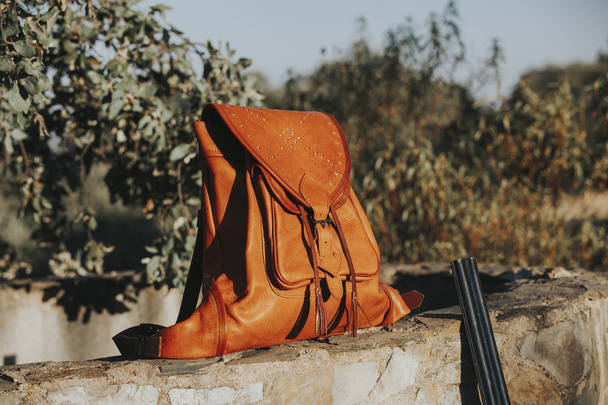 Leather bag in a stone wall at the countryside. Hunting concept. - Foto, afbeelding