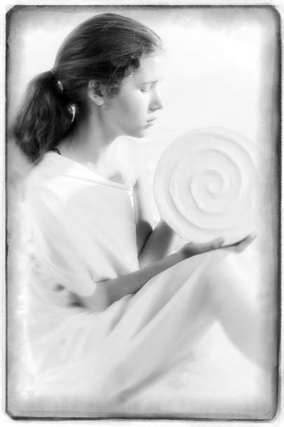 Kaunis nuori tyttö istuu profiilin ja tilalla pyöreä valkoinen maljakko
 - Valokuva, kuva