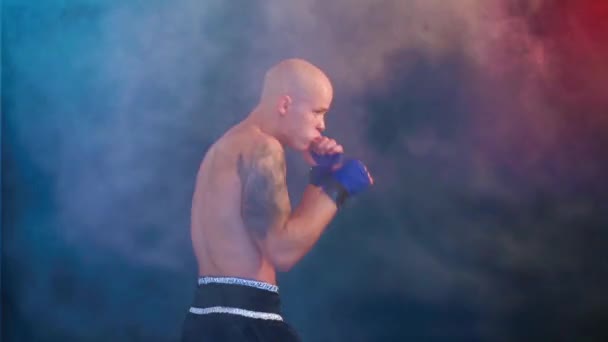 Muscular kickbox or muay thai fighter punching in smoke. - Metraje, vídeo
