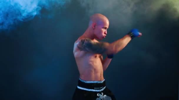 Muscular kickbox or muay thai fighter punching in smoke. - Imágenes, Vídeo