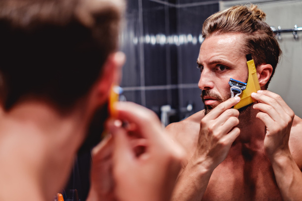 человек бреет бороду в ванной комнате - Фото, изображение