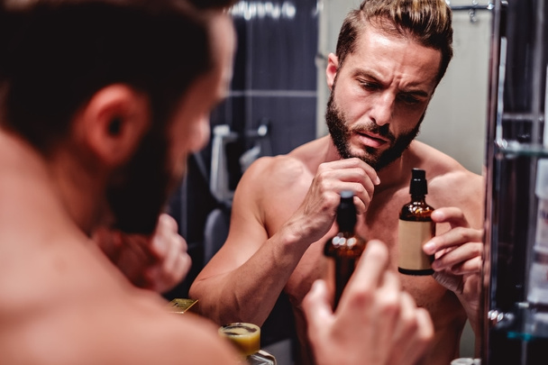 Hipster man holding bottle in the bathroom - Photo, Image