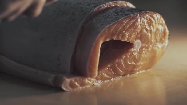 Sushi-Chef schneidet frischen Lachs an der Sushi-Bar. Ein Sushi-Mann schneidet mit seinem japanischen Messer ein Lachssteak. Zubereitung von Sushi Nigiri Fisch. Japanische Küche Rezepte. - Filmmaterial, Video