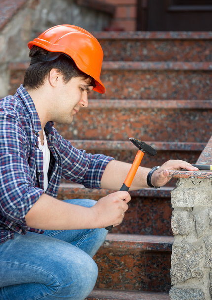 Junger Arbeiter mit Helm repariert alte Steintreppe - Foto, Bild