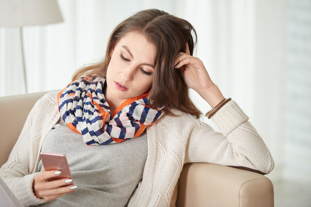 Woman sitting on sofa and reading message - Photo, Image