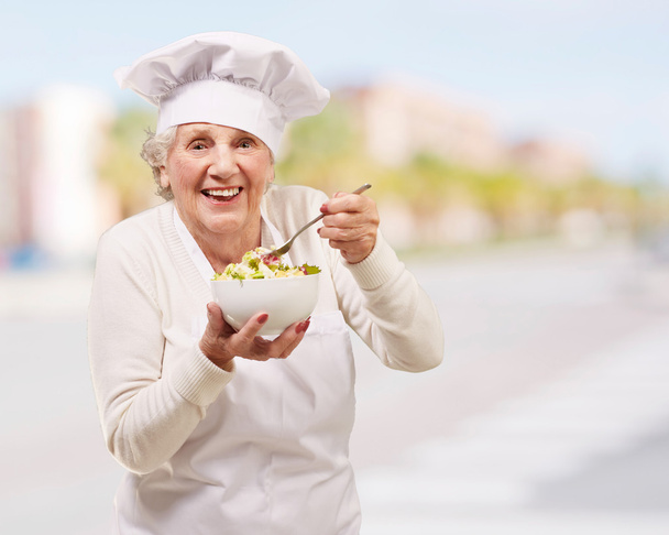 portrét ženy starší kuchař jíst salát na city - Fotografie, Obrázek