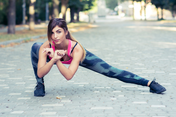 Young pretty woman stretching in the park before a run - Фото, зображення