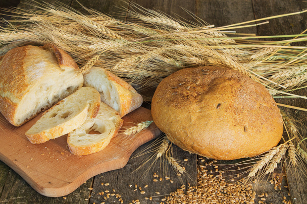 hele en gesneden brood met oren en tarwe - Foto, afbeelding