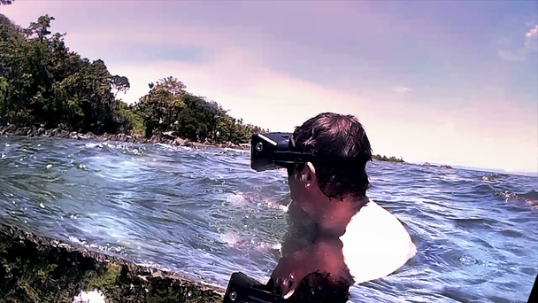 Man wearing VR virtual headset in ocean lagoon looks around in wonder - Footage, Video