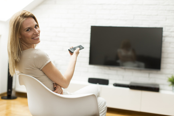 Woman with a tv remote control - Foto, imagen