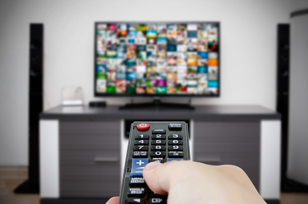 Ver televisão na moderna sala de TV. Mão segurando remoto
 - Foto, Imagem
