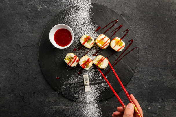 Γλυκό σούσι με κόκκινη μαρμελάδα φράουλα σε μαύρο πιάτο - Φωτογραφία, εικόνα
