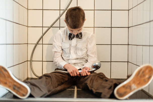 Unconscious boy holding running shower head - Valokuva, kuva