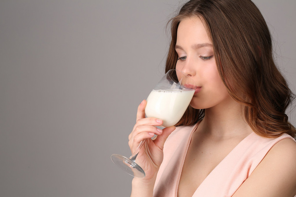 Girl drinking milk from a bocal. Close up. Gray background - Zdjęcie, obraz
