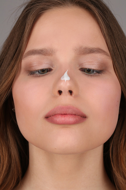 Girl with cream on her nose. Close up. Gray background - Foto, Imagen