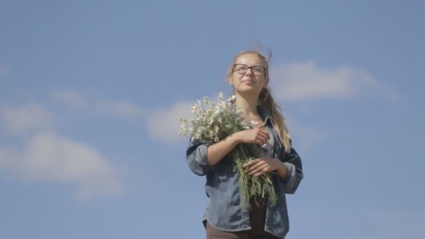 dívka s kyticí sedmikrásek na pozadí modré oblohy - Záběry, video