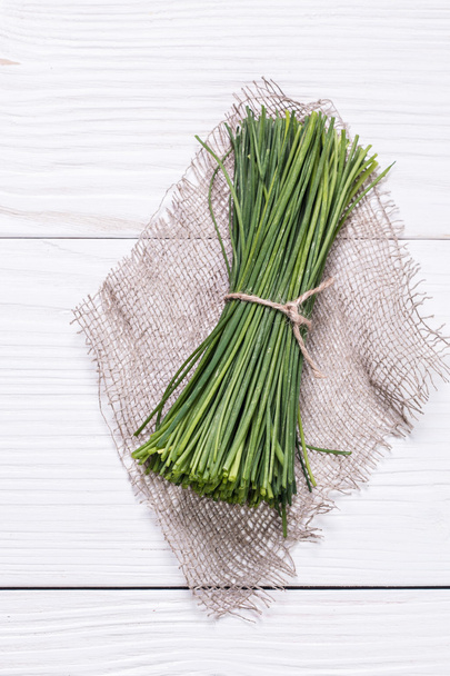 bunch of fresh chives on a wooden cutting board, selective focus - Foto, Imagem