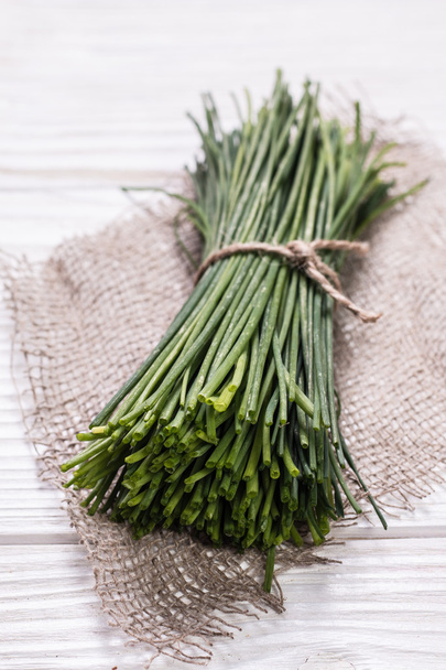 bunch of fresh chives on a wooden cutting board, selective focus - Fotografie, Obrázek