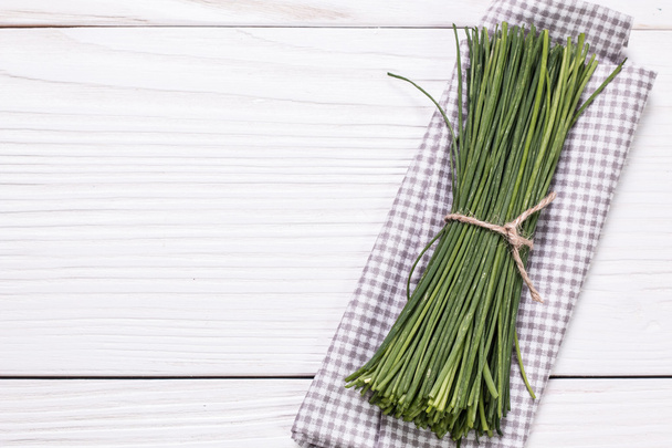 bunch of fresh chives on a wooden cutting board, selective focus - Fotografie, Obrázek