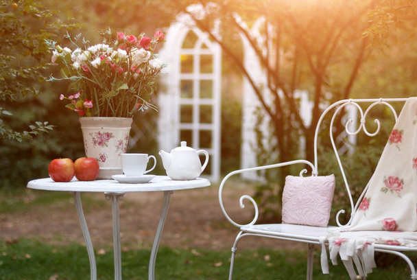 Білий порцеляновий набір для чаю або кави на столі в саду над розмитим зеленим фоном природи
. - Фото, зображення
