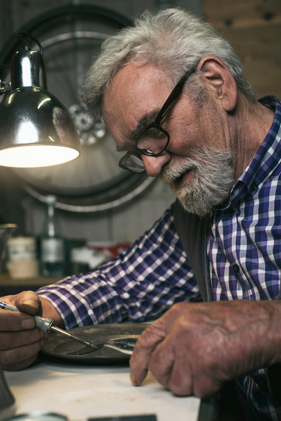 Homem sênior reparando placa de estanho
 - Foto, Imagem