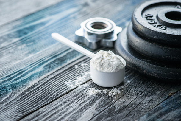 Classic dumbbell with protein powder on rustic wooden table - Photo, Image
