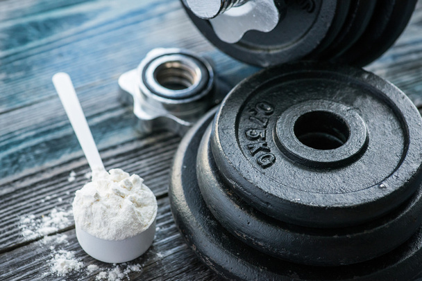 Classic dumbbell with protein powder on rustic wooden table - Фото, изображение