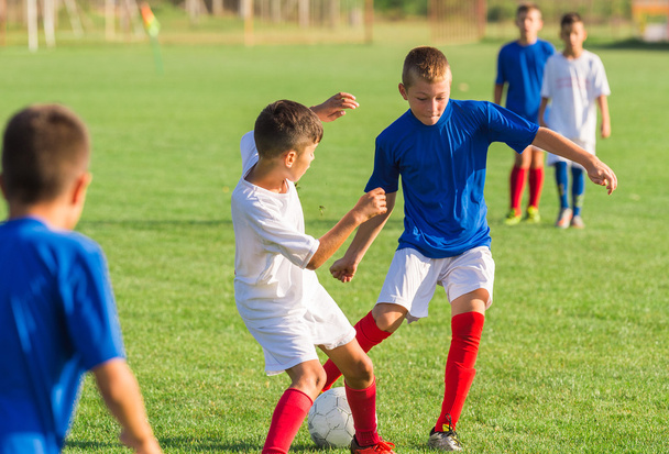 Αγόρια που παίζουν ποδόσφαιρο παιχνίδι ποδοσφαίρου στο αθλητικό πεδίο - Φωτογραφία, εικόνα
