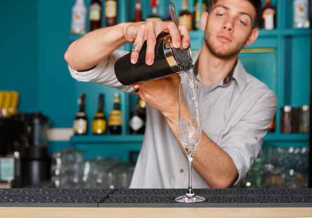 Joven barman guapo vertiendo bebida de cóctel en el vaso
 - Foto, imagen
